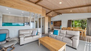 Una sala moderna con dos sofás, una mesa de centro de madera y una cocina con armarios de madera y un microondas empotrado.