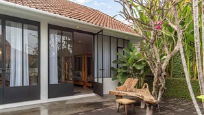 Une maison moderne avec un toit en tuiles, de grandes portes vitrées, une piscine et un banc en bois.