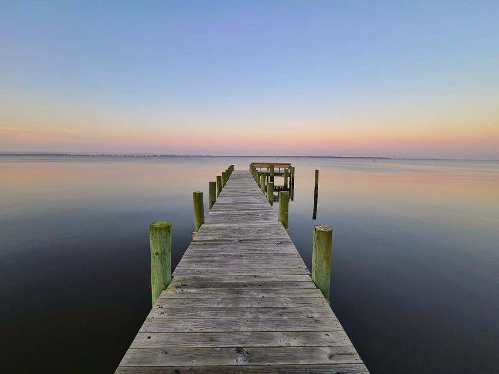 Un muelle de madera que se adentra en aguas tranquilas bajo un cielo despejado.