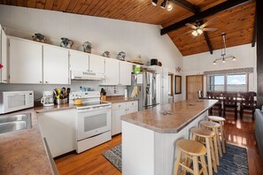 Enjoy cooking in this well-equipped kitchen with a large island and bar stools, featuring a microwave, stove, and refrigerator.