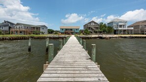 A wooden pier leading to a row of houses by a body of water.