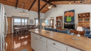 A spacious kitchen with a large island, wooden ceiling beams, and a dining area with a view.