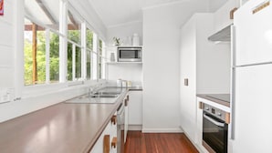 Une cuisine moderne avec des meubles blancs, un évier en acier inoxydable, un four à micro-ondes et un four traditionnel.