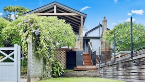 Une maison moderne avec un escalier en bois menant à un porche abrité.