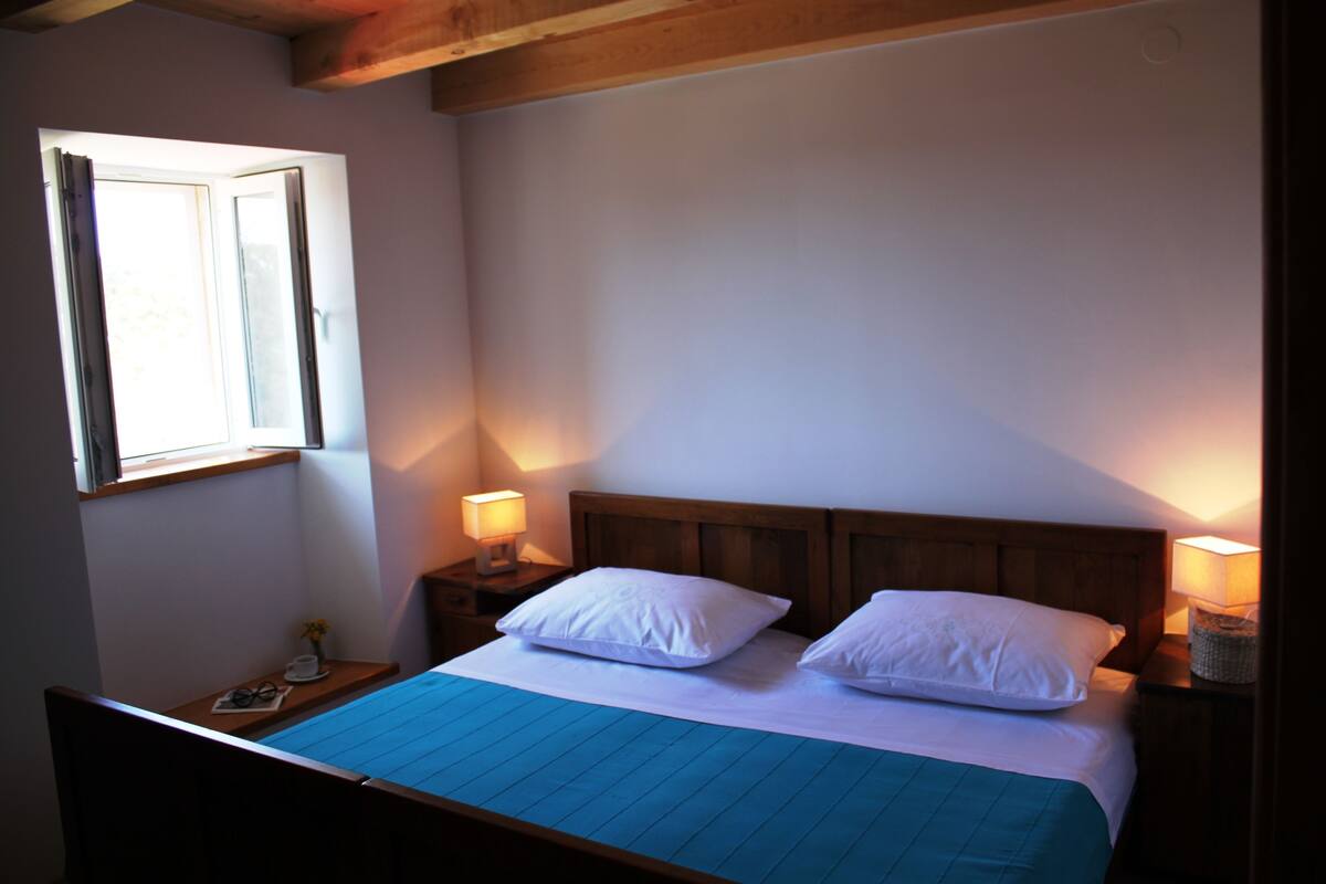 Ein Schlafzimmer mit einem Einzelbett, einem Nachttisch, einem Fenster und einer Lampe.
