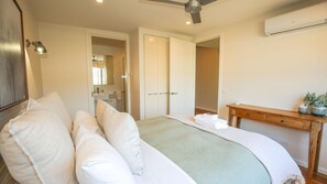 Une chambre à coucher comprenant un lit, une table de chevet et un appareil de climatisation.