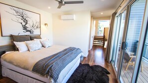 A bedroom with a bed, a ceiling fan, an air conditioning unit, and a view of the outside through a sliding glass door. - VILLA URBANE : Bright (Bright)