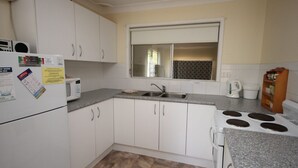 A compact kitchen with white cabinets, a microwave, a sink, and a stove.