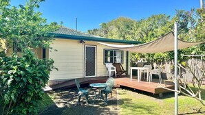 A small house with a patio area, a covered seating area, and a wooden deck.