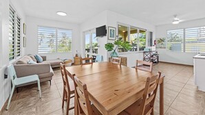 Un amplio espacio habitable con una mesa de comedor de madera, un sofá y un televisor montado en la pared.