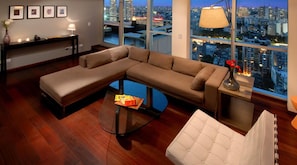 A modern living room with a L-shaped sectional sofa, a glass coffee table, and a view of the cityscape through large windows. - Amazing 2 BR/2.5 BA, 29/30th Floor Penthouse (Buenos Aires)