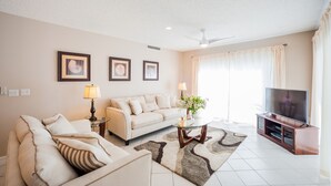 Ein Wohnzimmer mit Sofa, Couchtisch, TV-Schrank und gerahmten Bildern an der Wand.