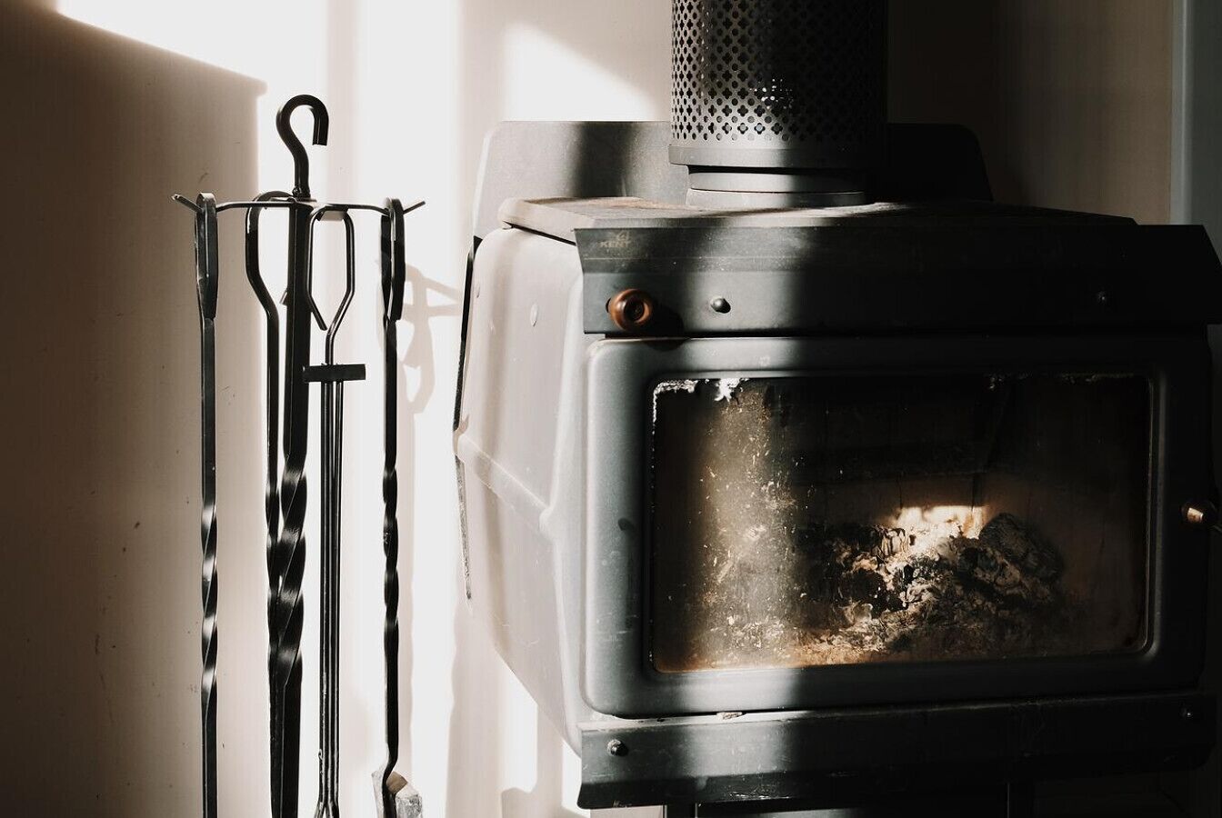A wood-burning stove with a metal rack beside it.