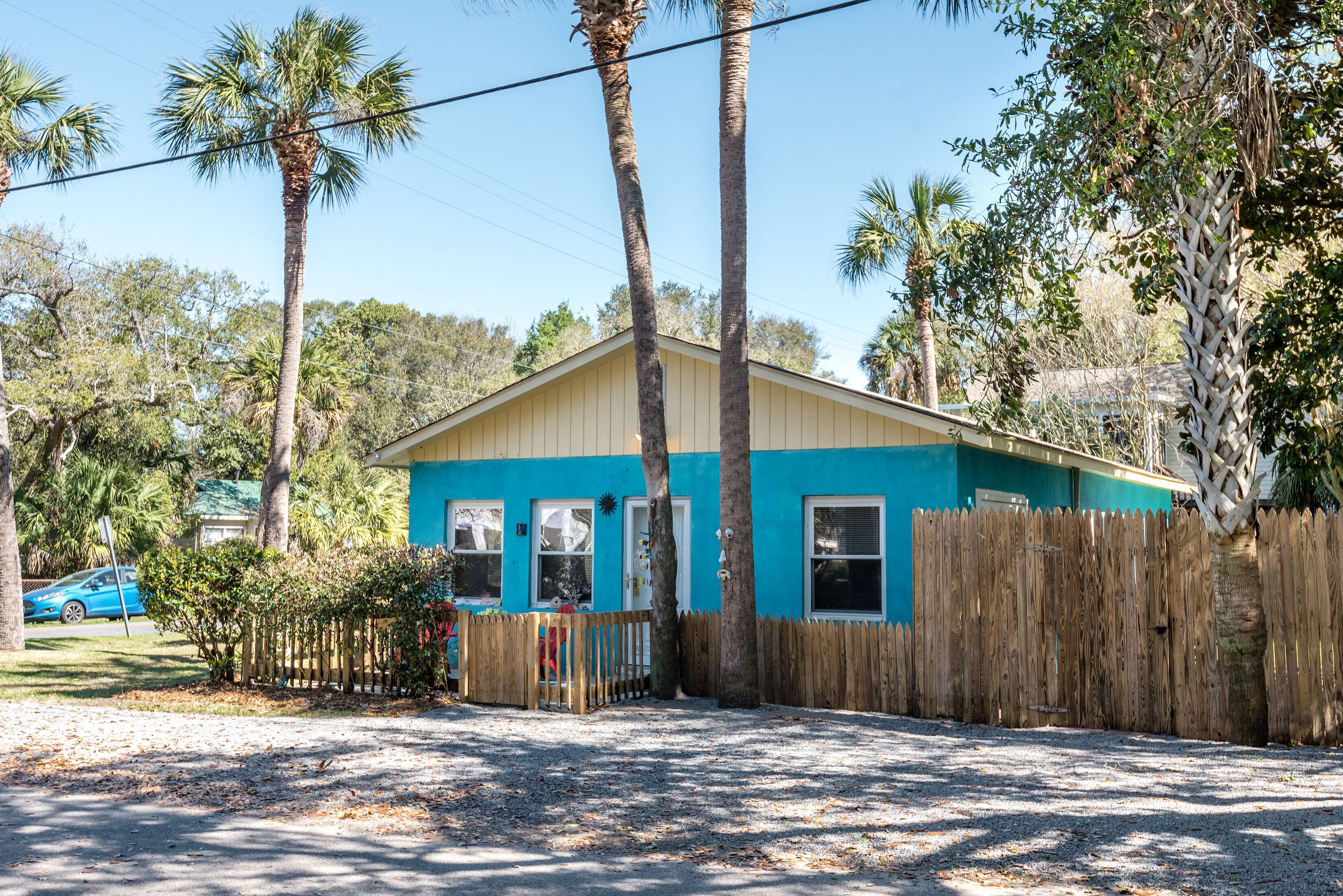 A small, single-story house with a blue exterior and a wooden fence.