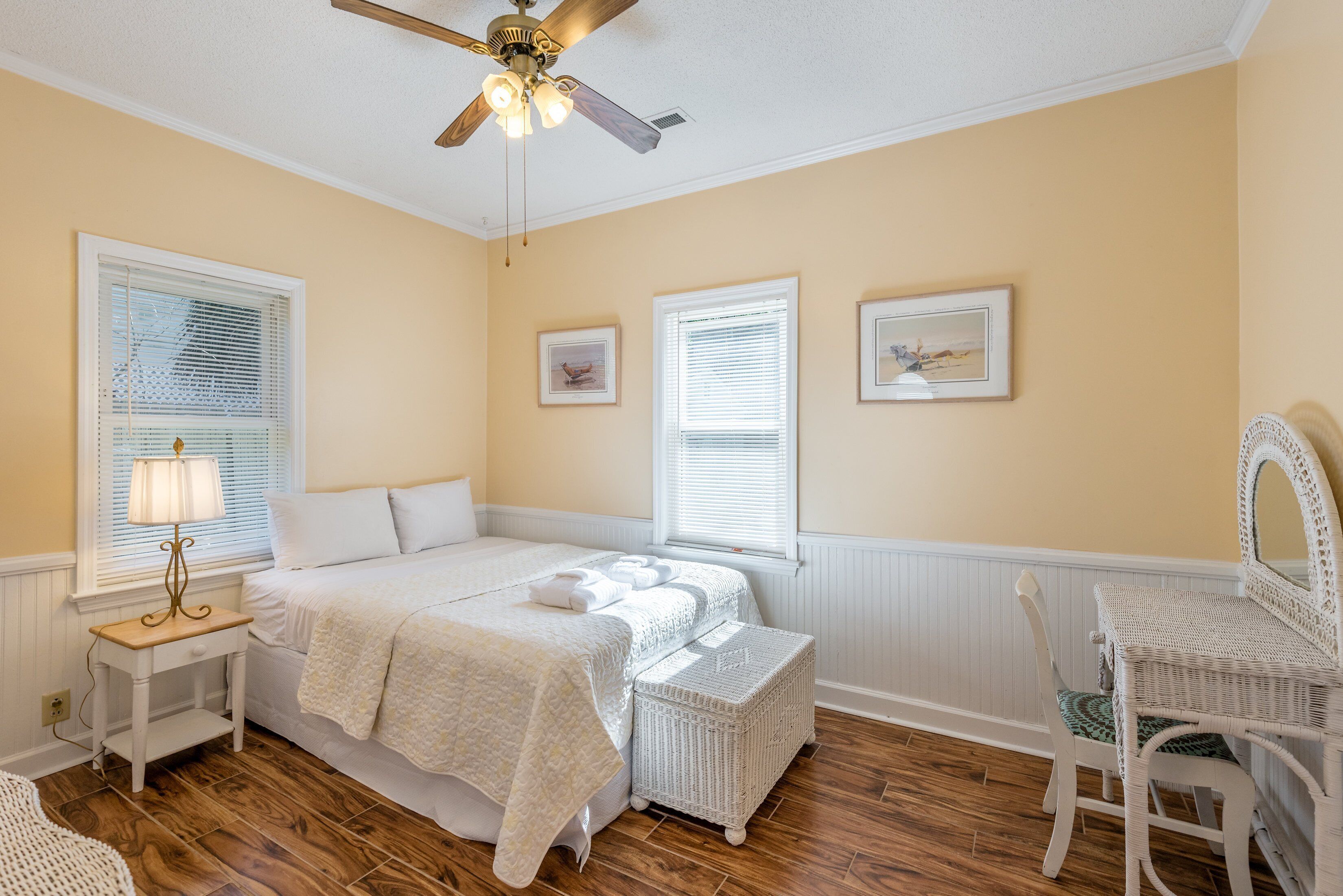 A bedroom with a bed, bedside tables, a chair, and a ceiling fan.