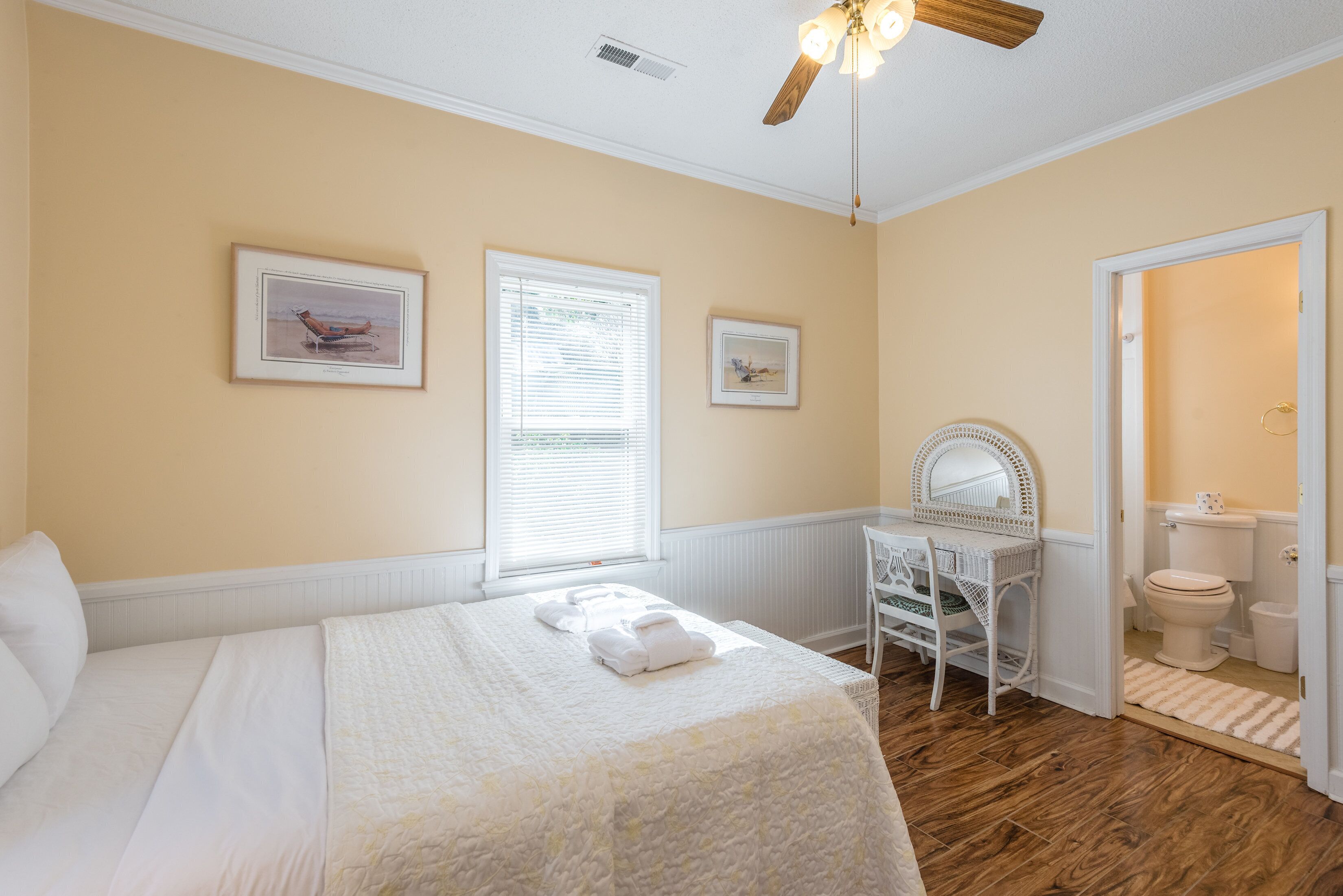 A bedroom with a bed, a desk, and a bathroom.