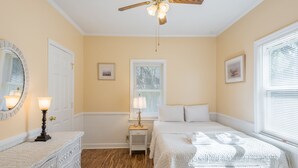 Ein Schlafzimmer mit einem Bett, Nachttischen, einem Deckenventilator und einem Fenster mit Jalousien.