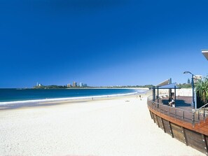 A beach with a wooden boardwalk and a covered seating area. - Renovated Beach House in the Heart of Mooloolaba (Mooloolaba)