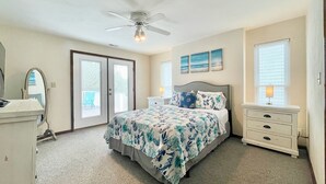 A bedroom with a bed, a nightstand, a dresser, a ceiling fan, and a window with blinds. - Just Steps to the Beach! (Virginia Beach)