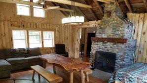 L’intérieur d’un chalet rustique, avec une cheminée en pierre, des meubles en bois et une grande fenêtre.