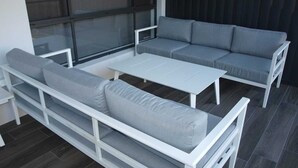 A modern outdoor seating area with a grey sofa and a white table. - Northern Haven Too, North Haven (North Haven)