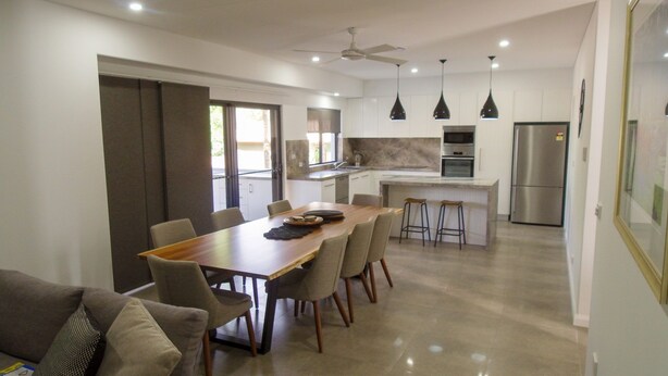 A modern kitchen with a central island, a dining area with a wooden table and chairs, and a built-in oven. - Northern Haven Too, North Haven (North Haven)