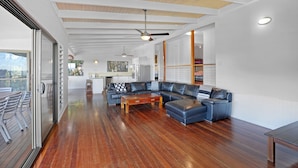 A spacious living area with a wooden floor, a leather sectional sofa, and a dining table.