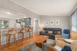 Een moderne woonkamer met een bank, salontafel en barstoelen.
