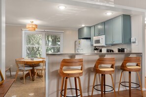 A kitchen with wooden chairs, a dining table, and teal cabinets. - 364 Close to the Beach and Wright Memorial! (Kill Devil Hills)