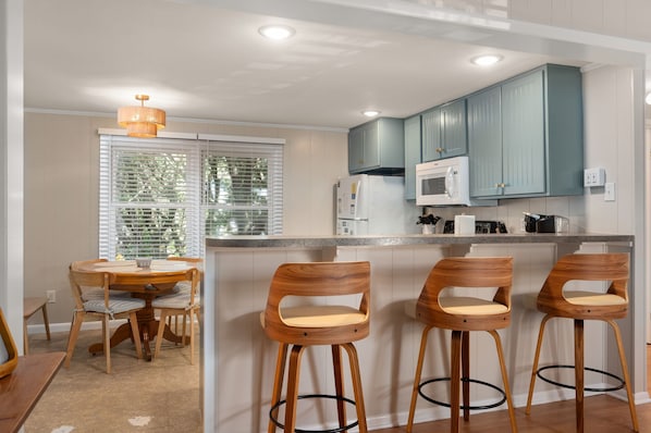 A kitchen with wooden chairs, a dining table, and teal cabinets.