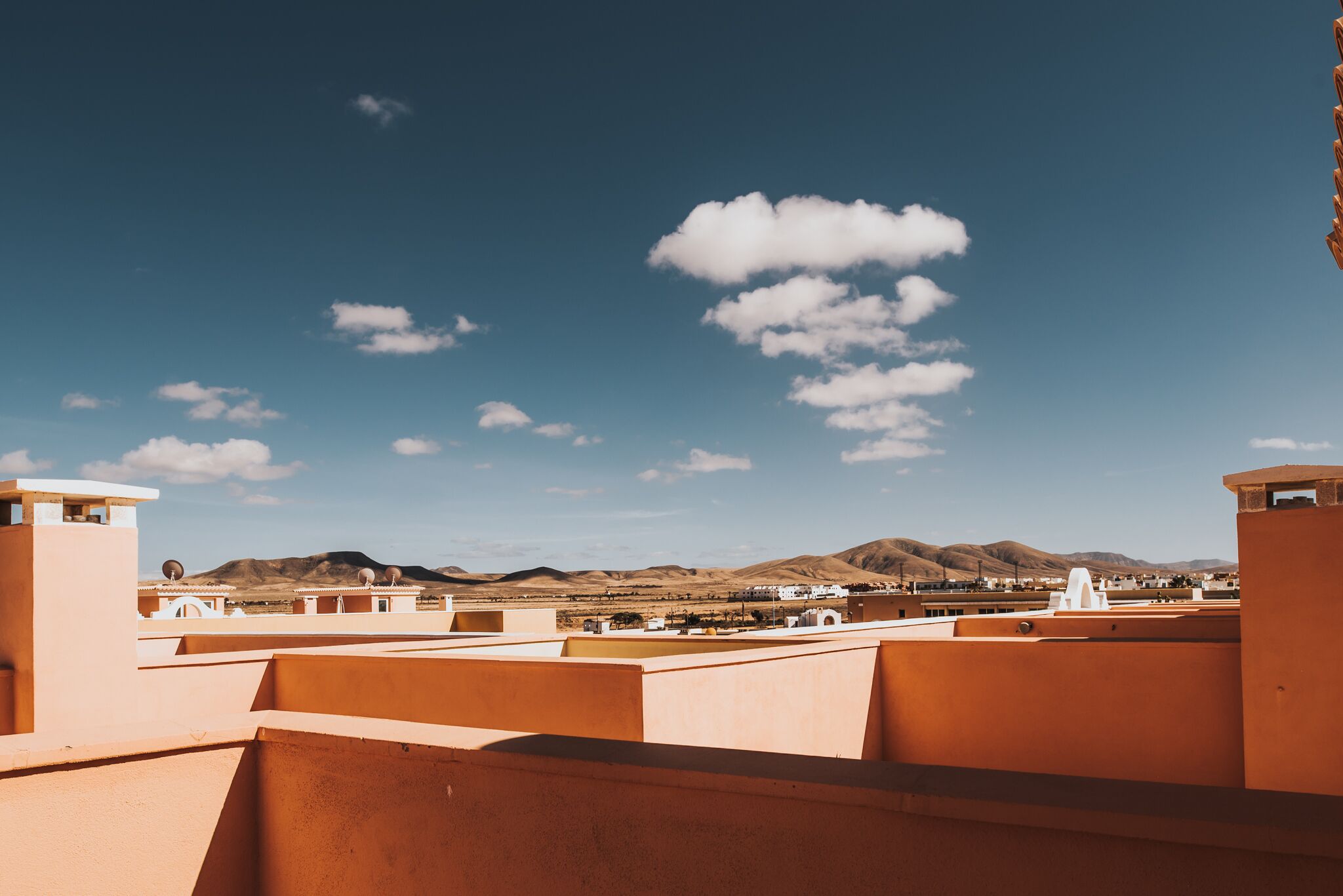 A desert landscape with mountains in the background and a clear blue sky.