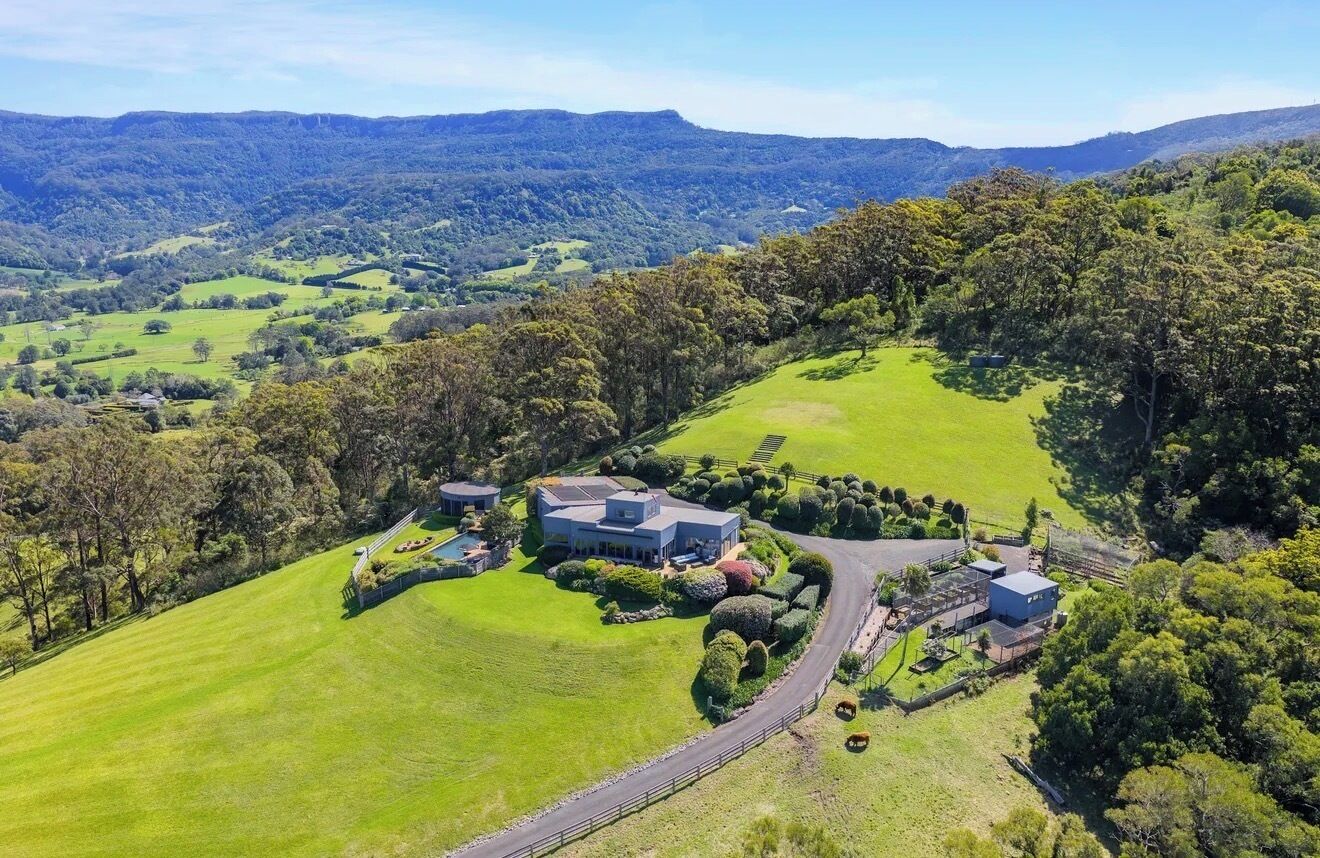 A large estate with multiple buildings, expansive green lawns, and a hilly landscape.