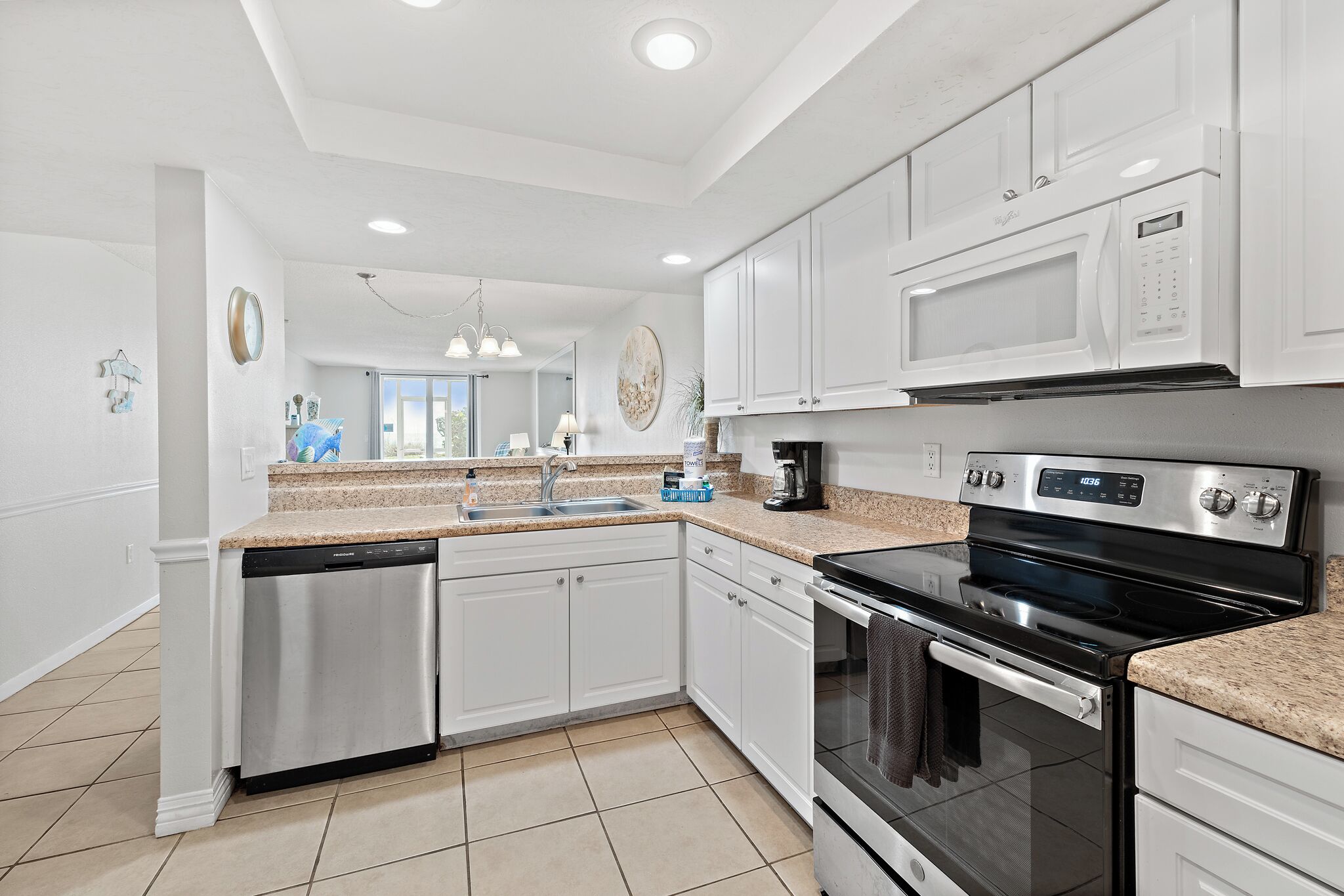 A kitchen with white cabinets, a dishwasher, a stove, and a microwave.