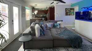 A modern living room with a sectional sofa, a coffee table, and a large aquarium.