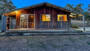 Eine rustikale Holzjagdhuette mit Veranda, großen Fenstern und einem überdachten Außenbereich.