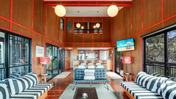 A spacious living area with a central sofa set, a coffee table, and a TV mounted on the wall.