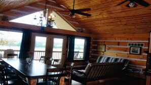 A wooden cabin interior with a dining table, chairs, a ceiling fan, and large windows. - ‘’Castle Colucci’’Magnet Indiana,a slice of Heaven where the world stands still. (Magnet)