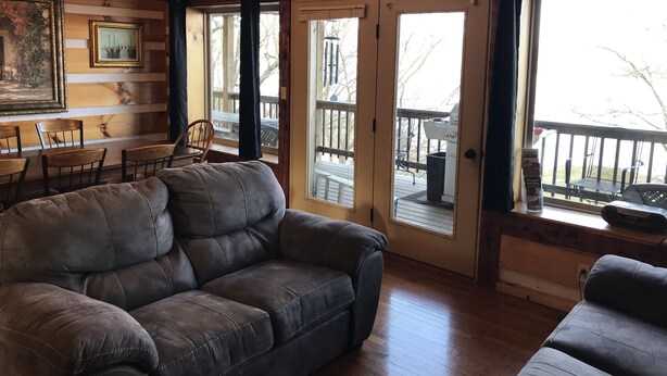 A cozy living room with a leather sofa, wooden walls, and large windows. - ‘’Castle Colucci’’Magnet Indiana,a slice of Heaven where the world stands still. (Magnet)