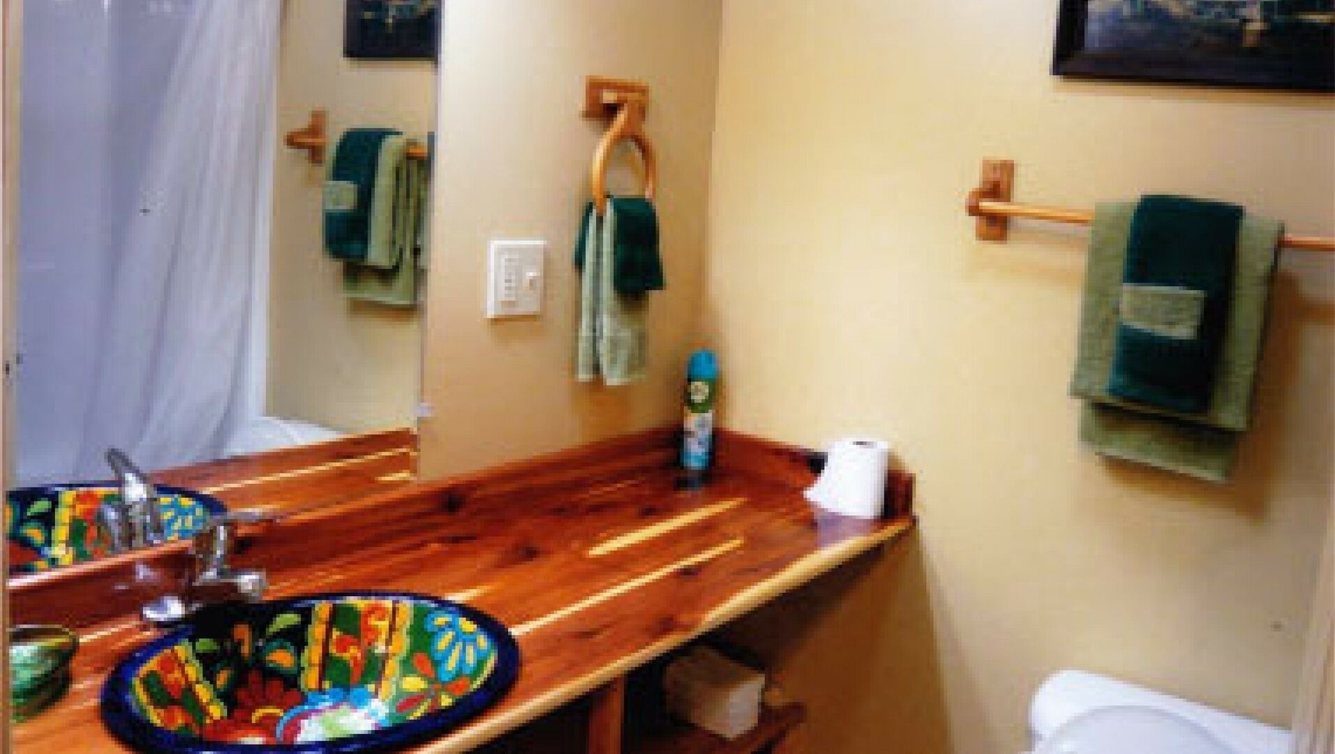 A bathroom with a wooden vanity, a mirror, a toilet, and a towel rack.