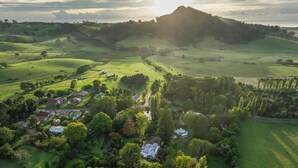 Paisaje rural con colinas ondulantes, un pequeño pueblo y una colina destacada al fondo.