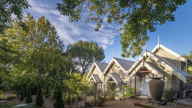 Un edificio de estilo arquitectónico tradicional, con una chimenea destacada y una gran urna decorativa en el jardín.