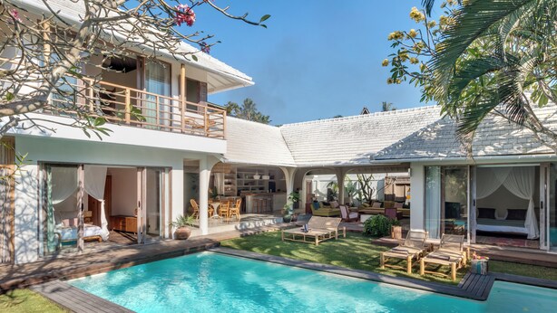 Ein zweistöckiges Haus mit Swimmingpool, Sitzgelegenheit im Freien und einer überdachten Terrasse.