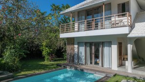 Une maison à deux étages avec une piscine, de grandes fenêtres et un balcon.
