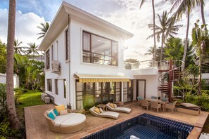 A modern two-story house with a pool, outdoor seating, and a spiral staircase.