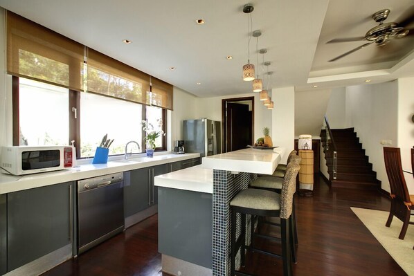 A modern kitchen with a large island, stainless steel appliances, and a view of the outdoors.