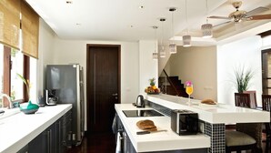 Una cocina moderna con una isla central, electrodomésticos integrados, iluminación colgante y un ventilador de techo.