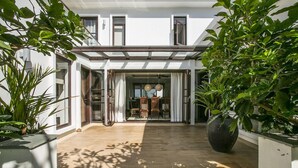Una casa moderna con un patio amplio, ventanas grandes y un comedor con sillas y una mesa.