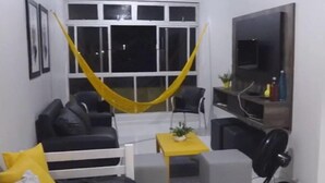 Un espace de vie compact comprenant un canapé, une petite table, un ventilateur et un téléviseur.