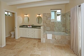Ein Badezimmer mit Badewanne, einer Duschkabine, einer Toilette und einem Waschtisch mit Waschbecken und Spiegeln.