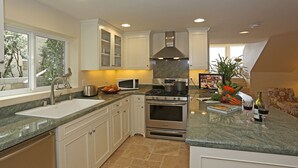 A modern kitchen with white cabinets, a stainless steel stove, and a granite countertop.